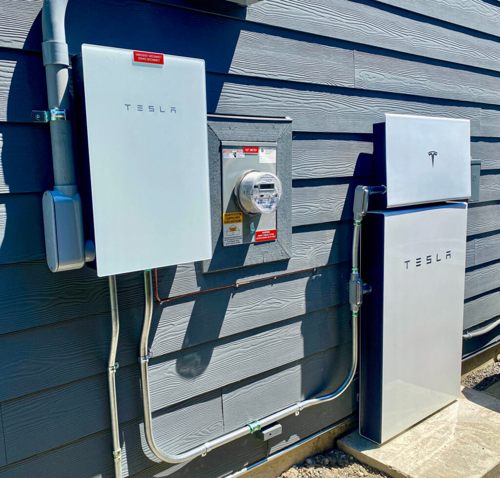 Tesla Powerwall Plus residential energy storage system on the side of a home.